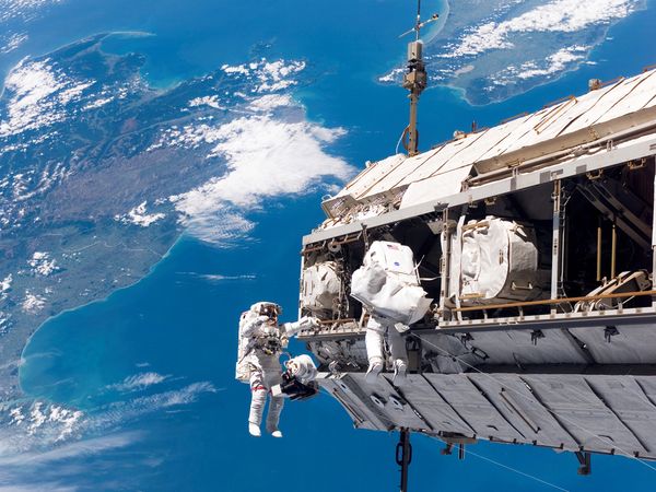 Astronauts work during a spacewalk outside the International Space Station orbiting Earth